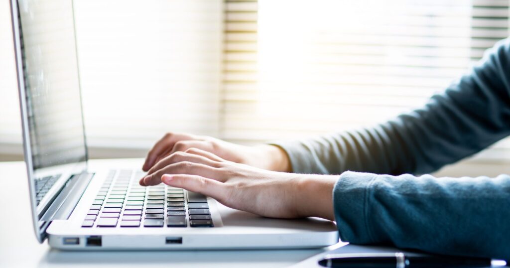Person typing on a laptop while organizing online accounts and passwords for digital estate planning