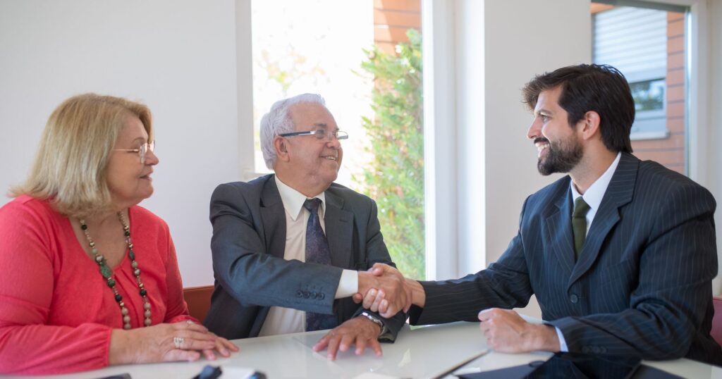 Senior couple shaking hands with an elder law attorney at their first meeting
