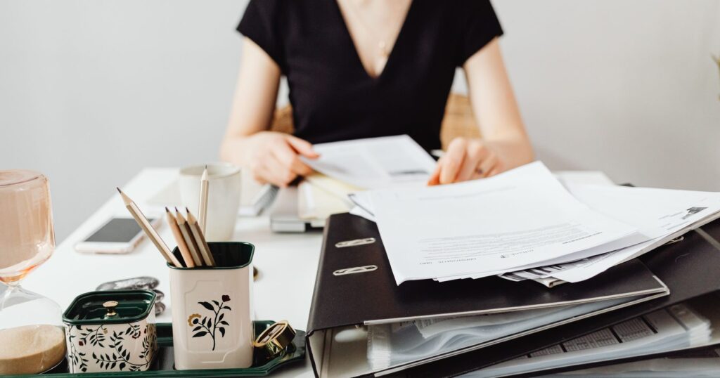 Person reviewing estate paperwork and a document binder while carrying out executor of a will duties